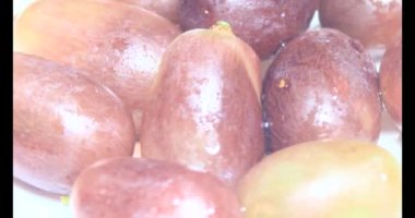 Tabakta üzüm var. Beyaz bir tabakta bir demet mor üzüm. Beyaz tabak dönüyor.