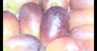 Tabakta üzüm var. Beyaz bir tabakta bir demet mor üzüm. Beyaz tabak dönüyor.