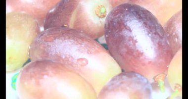 Tabakta üzüm var. Beyaz bir tabakta bir demet mor üzüm. Beyaz tabak dönüyor.