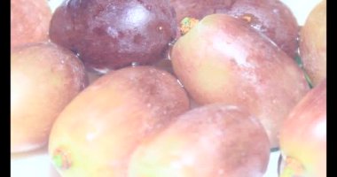 Tabakta üzüm var. Beyaz bir tabakta bir demet mor üzüm. Beyaz tabak dönüyor.