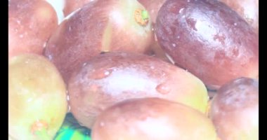 Tabakta üzüm var. Beyaz bir tabakta bir demet mor üzüm. Beyaz tabak dönüyor.