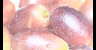 Tabakta üzüm var. Beyaz bir tabakta bir demet mor üzüm. Beyaz tabak dönüyor.