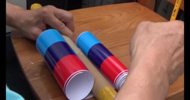 Adam araba gövdesine yapıştırmak için üç renkli çıkartma kullanıyor.