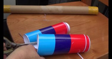 Adam araba gövdesine yapıştırmak için üç renkli çıkartma kullanıyor.