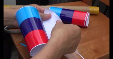 Adam araba gövdesine yapıştırmak için üç renkli çıkartma kullanıyor.