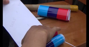 Adam araba gövdesine yapıştırmak için üç renkli çıkartma kullanıyor.