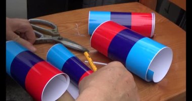 Adam araba gövdesine yapıştırmak için üç renkli çıkartma kullanıyor.