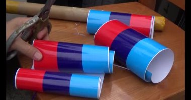 Adam araba gövdesine yapıştırmak için üç renkli çıkartma kullanıyor.