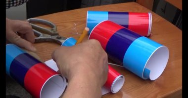 Adam araba gövdesine yapıştırmak için üç renkli çıkartma kullanıyor.