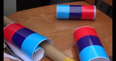 Adam araba gövdesine yapıştırmak için üç renkli çıkartma kullanıyor.