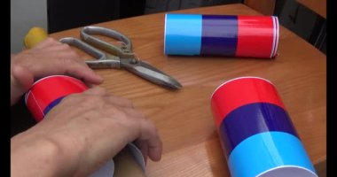 Adam araba gövdesine yapıştırmak için üç renkli çıkartma kullanıyor.