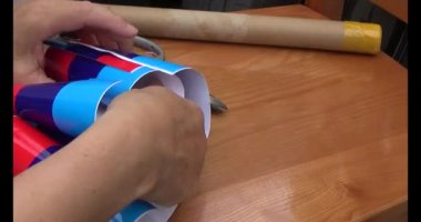 Adam araba gövdesine yapıştırmak için üç renkli çıkartma kullanıyor.