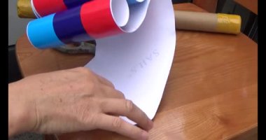 Adam araba gövdesine yapıştırmak için üç renkli çıkartma kullanıyor.