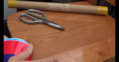 Adam araba gövdesine yapıştırmak için üç renkli çıkartma kullanıyor.