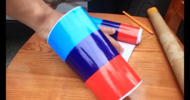 Adam araba gövdesine yapıştırmak için üç renkli çıkartma kullanıyor.