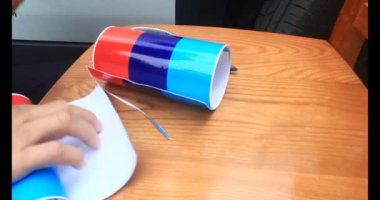 Adam araba gövdesine yapıştırmak için üç renkli çıkartma kullanıyor.