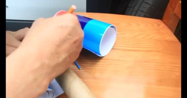 Adam araba gövdesine yapıştırmak için üç renkli çıkartma kullanıyor.