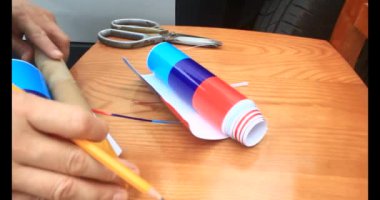 Adam araba gövdesine yapıştırmak için üç renkli çıkartma kullanıyor.