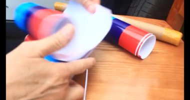 Adam araba gövdesine yapıştırmak için üç renkli çıkartma kullanıyor.