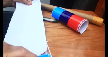 Adam araba gövdesine yapıştırmak için üç renkli çıkartma kullanıyor.