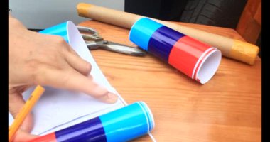 Adam araba gövdesine yapıştırmak için üç renkli çıkartma kullanıyor.