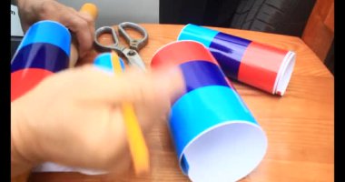 Adam araba gövdesine yapıştırmak için üç renkli çıkartma kullanıyor.