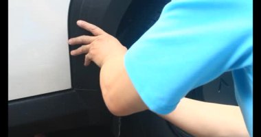 Adam bozuk arabayı tornavidayla tamir ediyor.