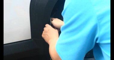 Adam bozuk arabayı tornavidayla tamir ediyor.