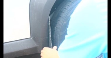 Adam bozuk arabayı tornavidayla tamir ediyor.