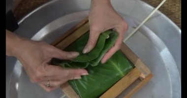  Vietnam 'da Chung keki yapan kadın. Banh chung gübre yapraklarıyla sarılmış, yapışkan pirinç, et ve fasulye.