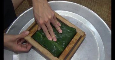 Vietnam 'da Chung keki yapan kadın. Banh chung gübre yapraklarıyla sarılmış, yapışkan pirinç, et ve fasulye.