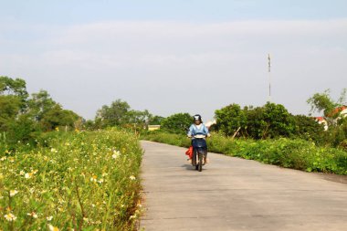 Vietnam 'ın kırsal kesimlerinde bisiklet ve motosiklet kullanan insanlar var.