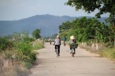 Vietnam 'ın kırsal kesimlerinde bisiklet ve motosiklet kullanan insanlar var.