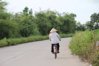 Vietnam 'ın kırsal kesimlerinde bisiklet ve motosiklet kullanan insanlar var.