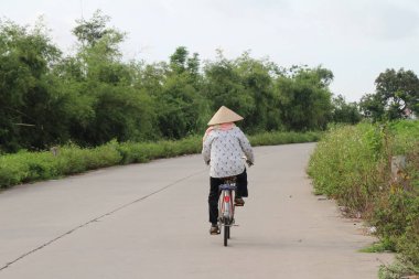Vietnam 'ın kırsal kesimlerinde bisiklet ve motosiklet kullanan insanlar var.