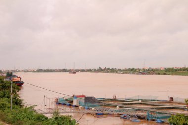 Nehir Vietnam 'da. Nehirde kayıklar ve gemiler, kıyılarda kırsal köyler, balık kafesleri, sebze tarlaları var.