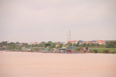 Nehir Vietnam 'da. Nehirde kayıklar ve gemiler, kıyılarda kırsal köyler, balık kafesleri, sebze tarlaları var.