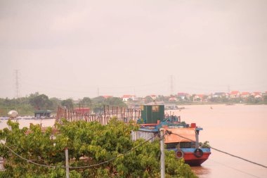 Nehir Vietnam 'da. Nehirde kayıklar ve gemiler, kıyılarda kırsal köyler, balık kafesleri, sebze tarlaları var.