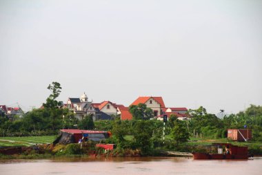 Nehir Vietnam 'da. Nehirde kayıklar ve gemiler, kıyılarda kırsal köyler, balık kafesleri, sebze tarlaları var.