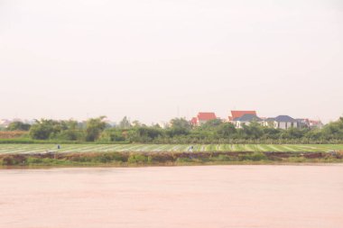 Nehir Vietnam 'da. Nehirde kayıklar ve gemiler, kıyılarda kırsal köyler, balık kafesleri, sebze tarlaları var.