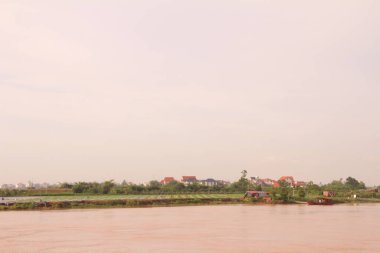 Nehir Vietnam 'da. Nehirde kayıklar ve gemiler, kıyılarda kırsal köyler, balık kafesleri, sebze tarlaları var.