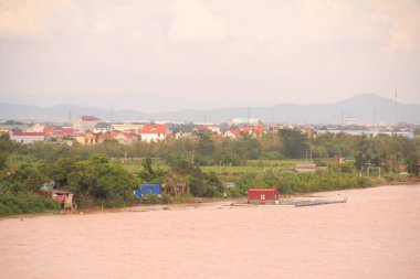 Nehir Vietnam 'da. Nehirde kayıklar ve gemiler, kıyılarda kırsal köyler, balık kafesleri, sebze tarlaları var.