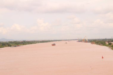 Nehir Vietnam 'da. Nehirde kayıklar ve gemiler, kıyılarda kırsal köyler, balık kafesleri, sebze tarlaları var.