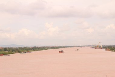 Nehir Vietnam 'da. Nehirde kayıklar ve gemiler, kıyılarda kırsal köyler, balık kafesleri, sebze tarlaları var.