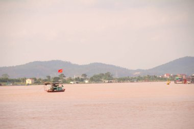 Nehir Vietnam 'da. Nehirde kayıklar ve gemiler, kıyılarda kırsal köyler, balık kafesleri, sebze tarlaları var.