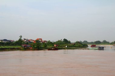 Nehir Vietnam 'da. Nehirde kayıklar ve gemiler, kıyılarda kırsal köyler, balık kafesleri, sebze tarlaları var.