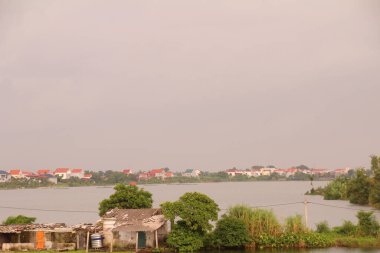 Nehir Vietnam 'da. Nehirde kayıklar ve gemiler, kıyılarda kırsal köyler, balık kafesleri, sebze tarlaları var.