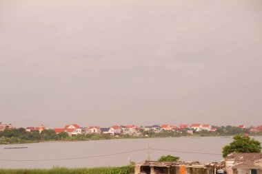 Nehir Vietnam 'da. Nehirde kayıklar ve gemiler, kıyılarda kırsal köyler, balık kafesleri, sebze tarlaları var.