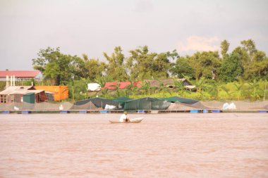 Nehir Vietnam 'da. Nehirde kayıklar ve gemiler, kıyılarda kırsal köyler, balık kafesleri, sebze tarlaları var.