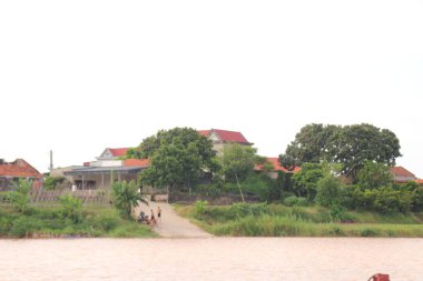 Nehir Vietnam 'da. Nehirde kayıklar ve gemiler, kıyılarda kırsal köyler, balık kafesleri, sebze tarlaları var.